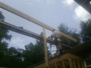 Carpenter setting a ridge beam over a new addition frame — Ice Dam Removal by Roofing Brothers in Bloomington